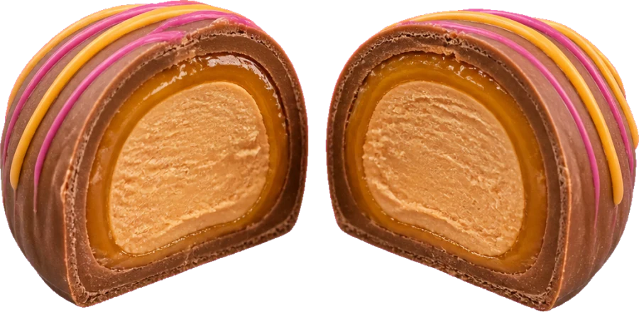 A truffle cut in half showing a milk chocolate shell, a caramel layer and a peanut butter center